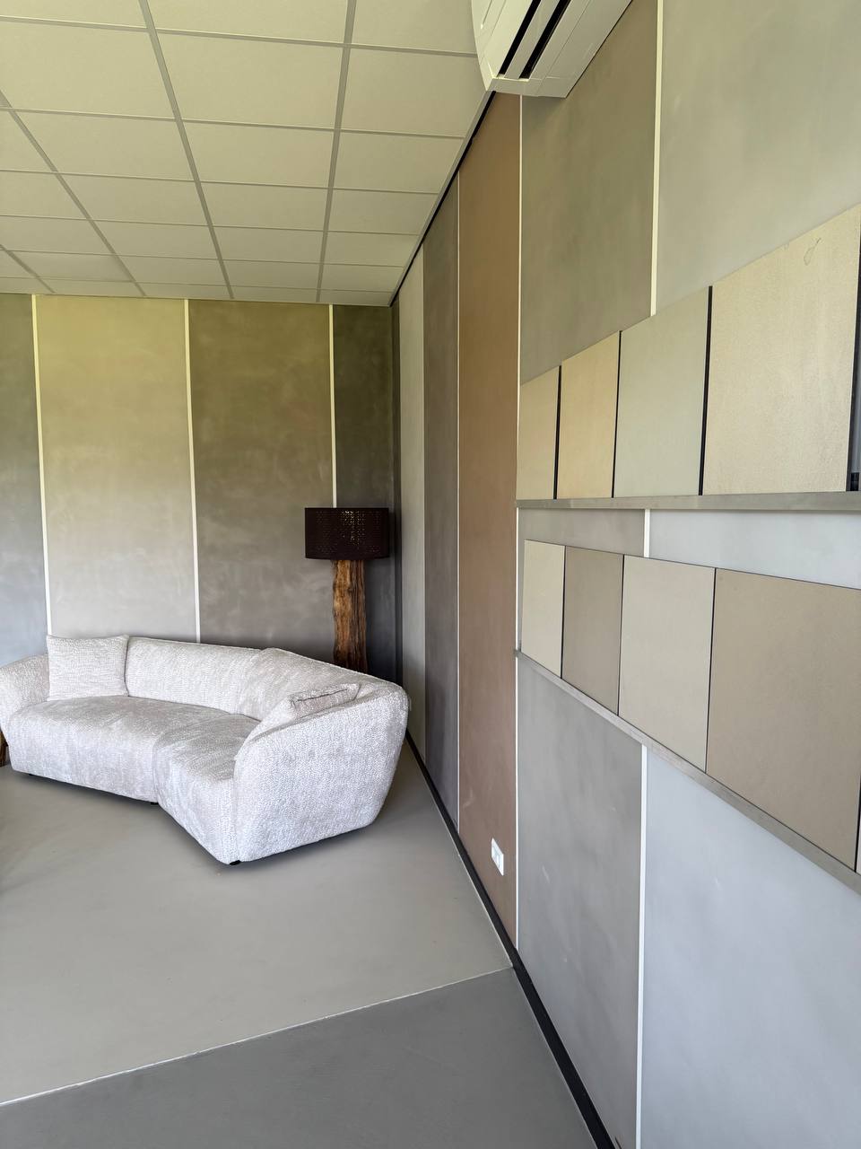 Loungehoek in onze showroom met beton ciré wandpanelen en uitgestalde stalen